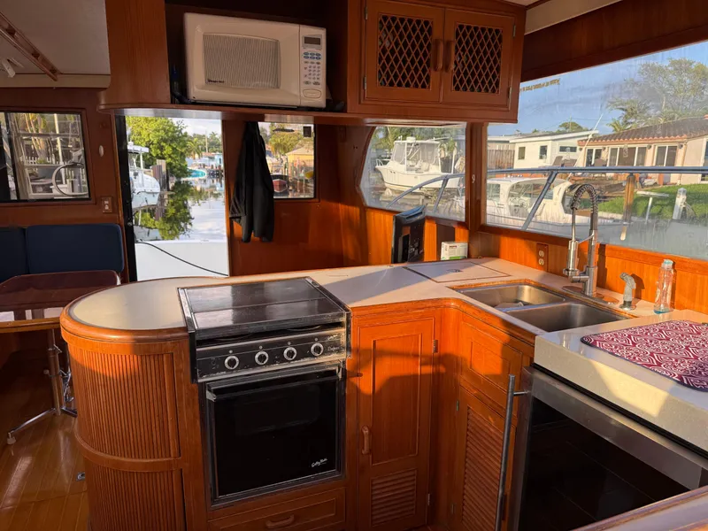 Slide: The Image of 1988 Hi-Star 44 Convertible yacht kitchen with stove, microwave, and sink, featuring wooden cabinetry. - 5