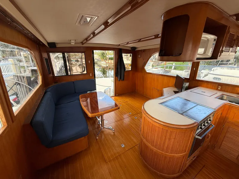 Slide: The Image of 1988 Hi-Star 44 Convertible yacht interior with wood finish, blue seating, and kitchen area. - 7