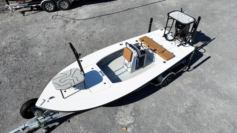 Slide: The Image of 2022 Xplor X7 boat on trailer, aerial view, white deck, brown seating, gravel background. - 0