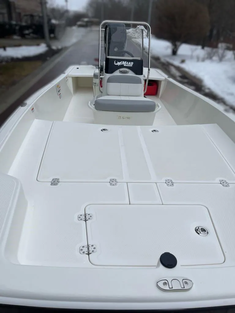 Slide: The Image of 2025 Mako Pro Skiff 17 CC boat, white deck, center console, parked on snowy street. - 5