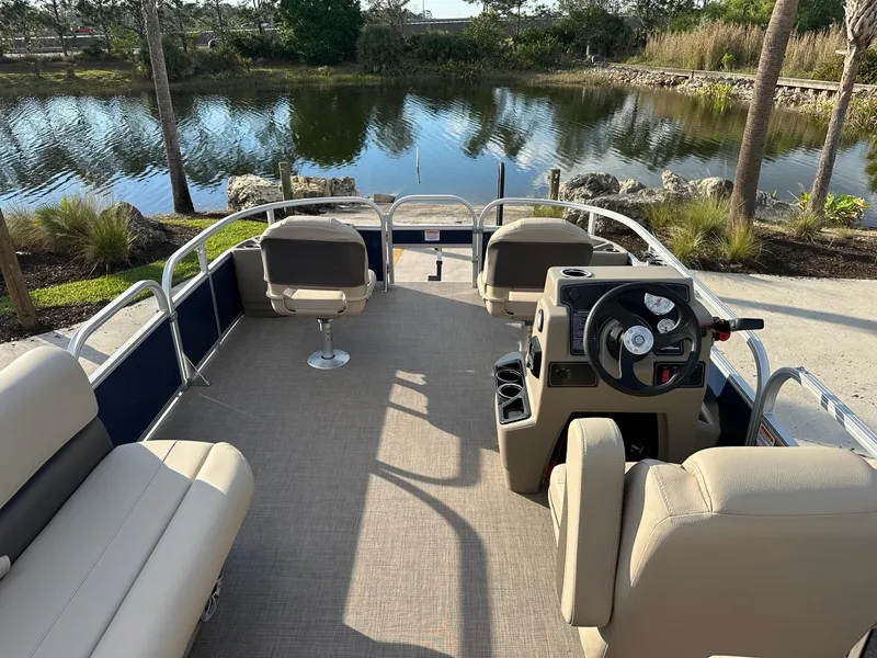 Slide: The Image of 2025 Sun Tracker Bass Buggy 18 DLX pontoon boat interior by a serene lake. - 4