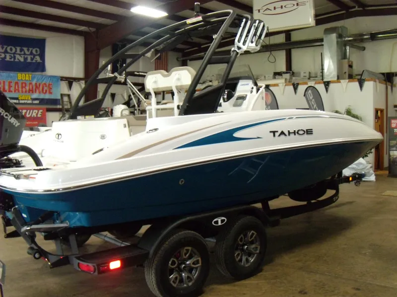 Slide: The Image of 2025 Tahoe 2150 CC boat on trailer in showroom, blue and white design. - 2