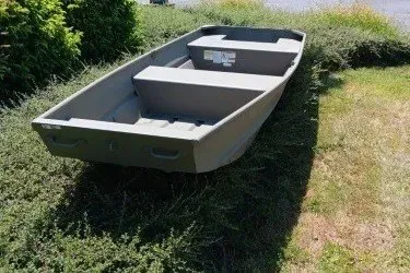 The Image of 2025 Tracker Grizzly 14 Jon boat on grass, showcasing sturdy design and spacious interior. - 0