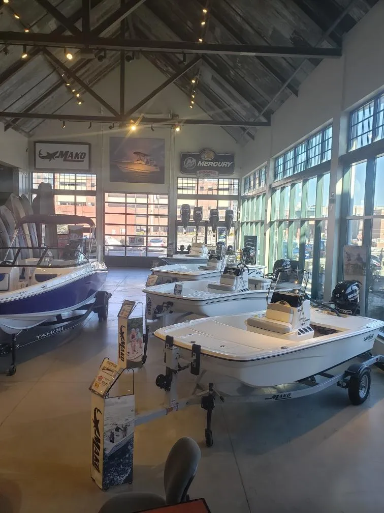 Slide: The Image of 2025 Mako Pro Skiff 15 CC displayed in a showroom with other boats. - 2