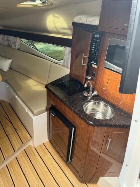 Slide: The Image of 2014 Regal 28 Express cabin interior with kitchenette, sink, and seating area. - 18