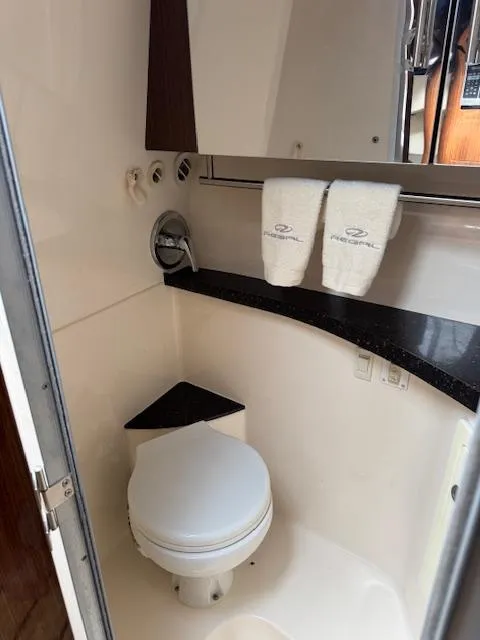 Slide: The Image of 2014 Regal 28 Express boat bathroom with toilet, countertop, and branded towels. - 20