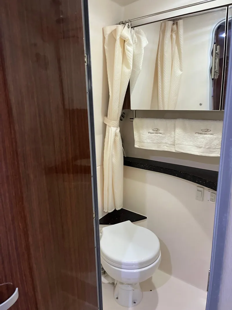Slide: The Image of 2014 Regal 28 Express boat bathroom with toilet, mirror, and shower curtain. - 7