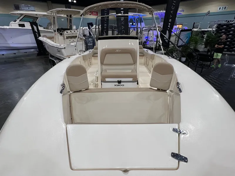Slide: The Image of 2025 Scout 195 Sportfish boat interior at a showroom, featuring seating and storage. - 2