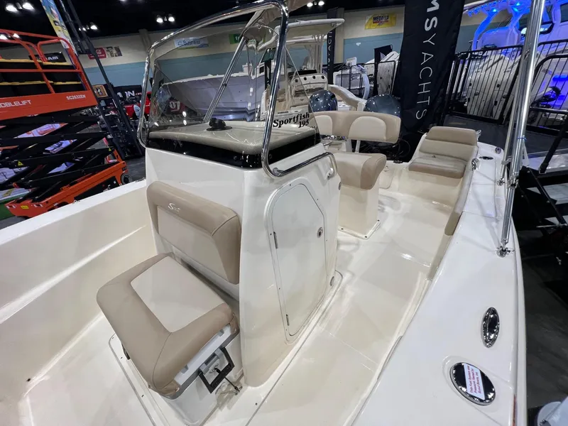 Slide: The Image of 2025 Scout 195 Sportfish boat interior with beige seating and console at a showroom. - 4