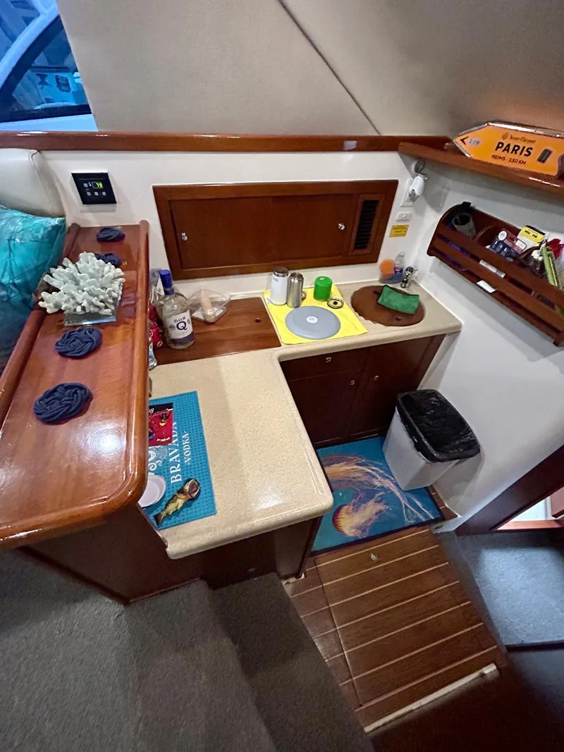 Slide: The Image of 2002 Riviera Convertible 37 yacht interior with compact kitchen and wooden accents. - 10