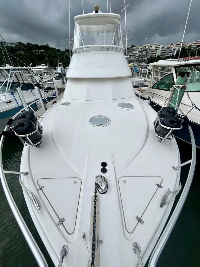 Slide: The Image of 2002 Riviera Convertible 37 yacht docked in marina, overcast sky, sleek white design. - 4