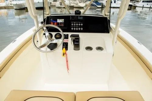 Slide: The Image of 2025 Scout 215 XSF boat console with steering wheel and controls, docked at marina. - 10