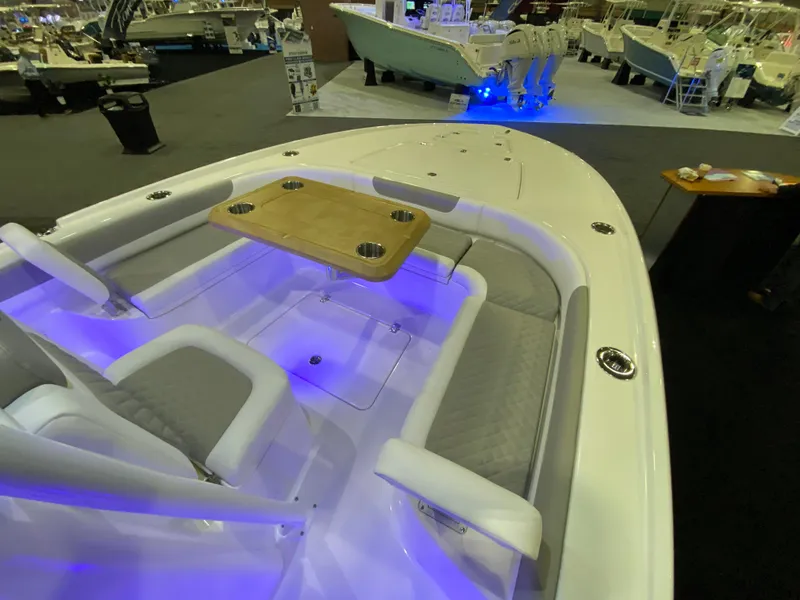 Slide: The Image of 2025 Caymas 26 HB boat interior with seating and table, illuminated by blue LED lights. - 9