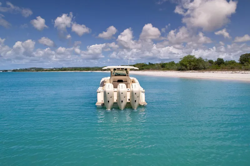 Slide: The Image of 2024 Scout 377 LXF boat anchored in clear turquoise water near a sandy beach. - 10