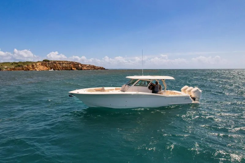 Slide: The Image of 2024 Scout 377 LXF boat cruising on open water under clear blue sky. - 12