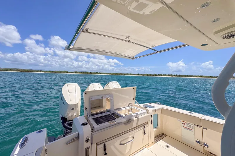 Slide: The Image of 2024 Scout 377 LXF boat with open deck, ocean view, and clear blue sky. - 31