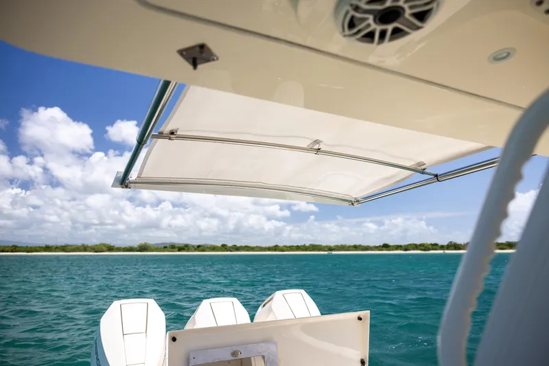 Slide: The Image of 2024 Scout 377 LXF boat with canopy, cruising on clear blue water under a sunny sky. - 33