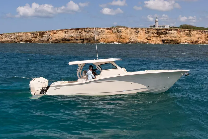 Slide: The Image of 2024 Scout 377 LXF boat cruising near rocky coastline with lighthouse in background. - 35
