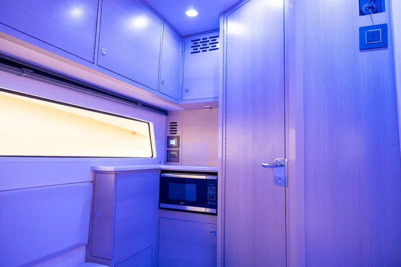 Slide: The Image of 2024 Scout 377 LXF interior with modern cabinetry and microwave, illuminated in blue lighting. - 47