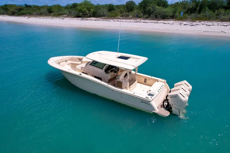 Slide: The Image of 2024 Scout 377 LXF boat in turquoise water near a sandy beach. - 6