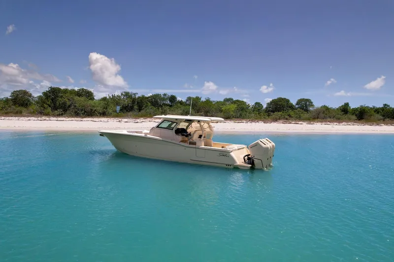 Slide: The Image of 2024 Scout 377 LXF boat anchored in clear turquoise water near a sandy beach. - 8