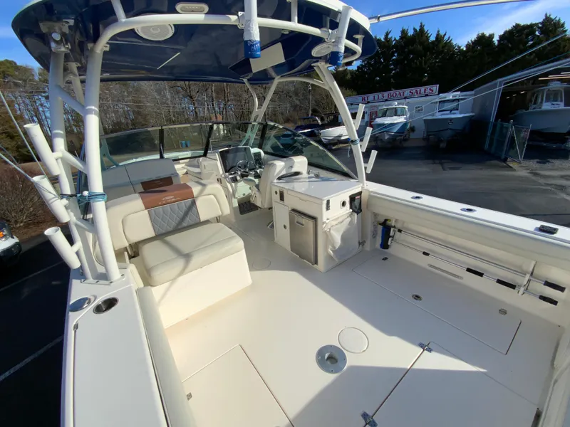 Slide: The Image of 2019 Cobia 280 Dual Console boat interior with seating and helm, parked outdoors. - 12