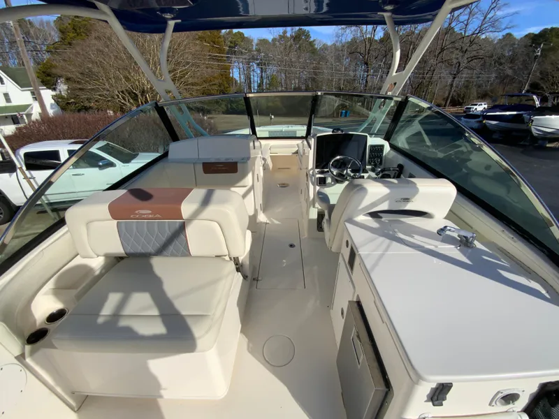 Slide: The Image of 2019 Cobia 280 Dual Console boat interior with seating and helm, parked outdoors. - 15
