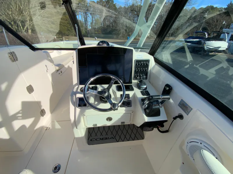 Slide: The Image of 2019 Cobia 280 Dual Console boat cockpit with steering wheel and control panel. - 16