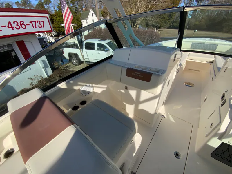 Slide: The Image of 2019 Cobia 280 Dual Console boat interior with seating and dashboard, parked near a dealership. - 17