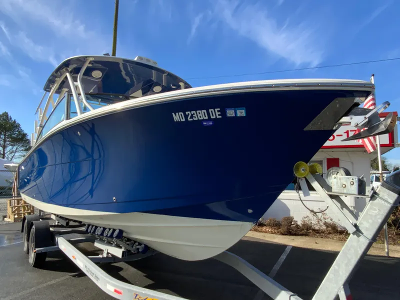 Slide: The Image of 2019 Cobia 280 Dual Console boat on trailer, blue hull, parked outdoors. - 3