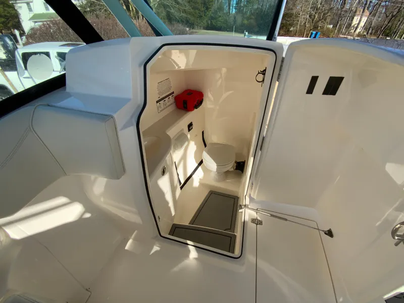 Slide: The Image of 2019 Cobia 280 Dual Console boat interior with compact marine toilet. - 30