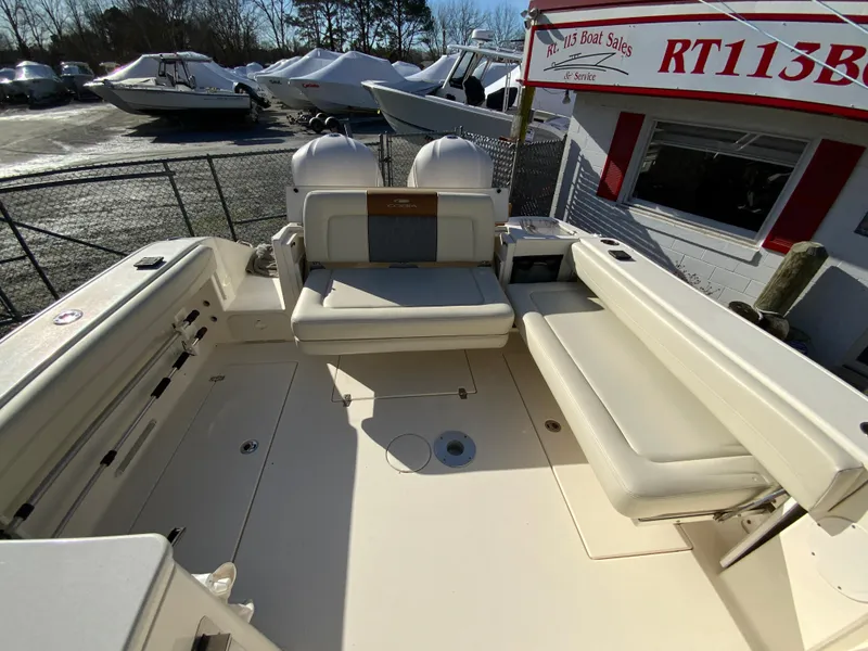 Slide: The Image of 2019 Cobia 280 Dual Console boat interior with seating and storage, displayed at a boat sales lot. - 34