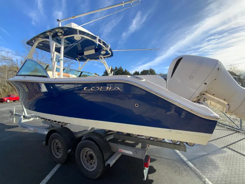 Slide: The Image of 2019 Cobia 280 Dual Console boat on trailer under clear blue sky. - 7