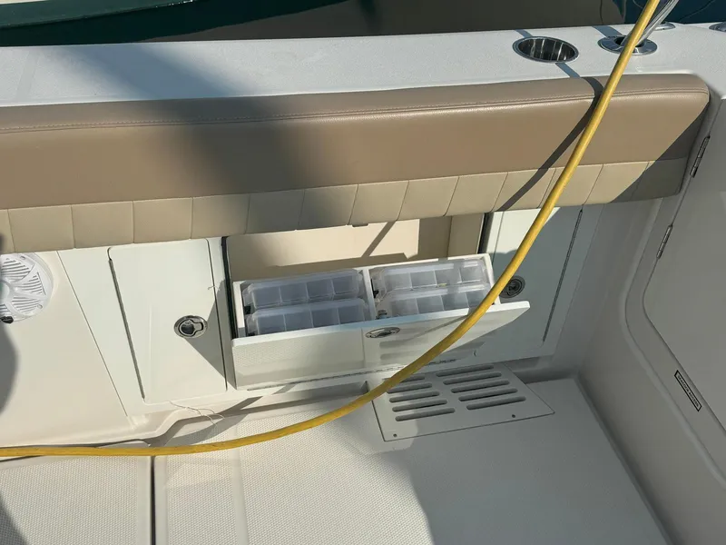 Slide: The Image of 2019 Sailfish 360 CC boat storage compartment with tackle boxes and cushioned seating. - 15