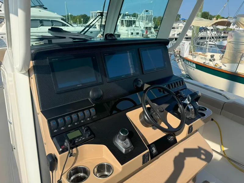 Slide: The Image of 2019 Sailfish 360 CC boat helm with dual screens and steering wheel in marina setting. - 33