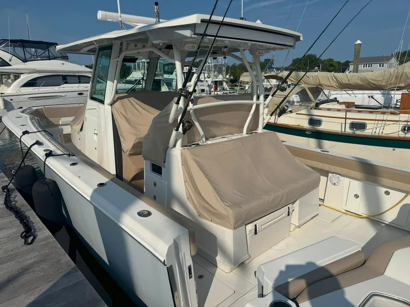 Slide: The Image of 2019 Sailfish 360 CC boat docked at marina, featuring covered seating and fishing rods. - 8