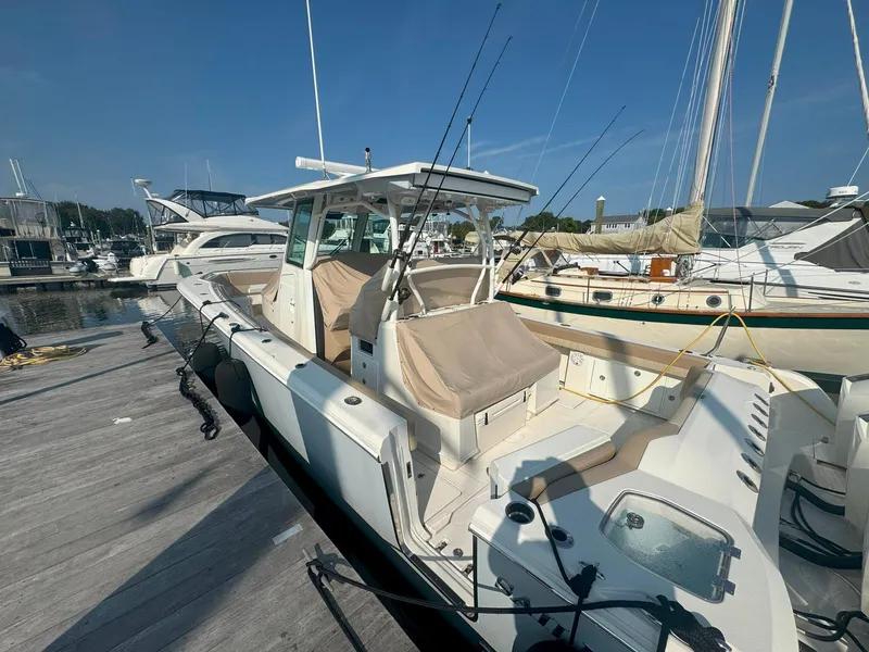 Slide: The Image of 2019 Sailfish 360 CC boat docked at marina, featuring fishing rods and covered seating. - 9