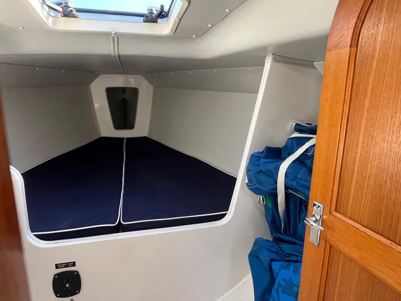 Slide: The Image of 2005 J Boats J/100 cabin interior with blue cushions and wooden door. - 10