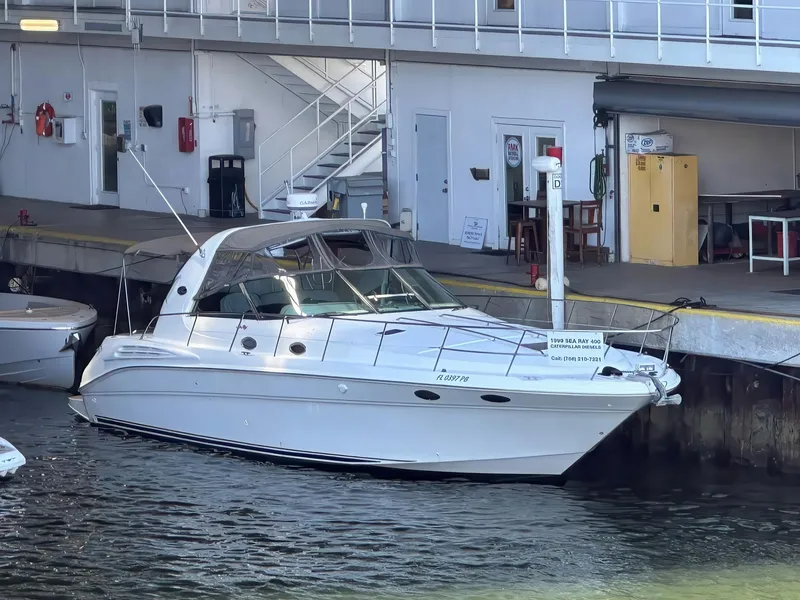 Slide: The Image of 1999 Sea Ray 400 Sundancer yacht docked at marina, white exterior, calm water. - 1