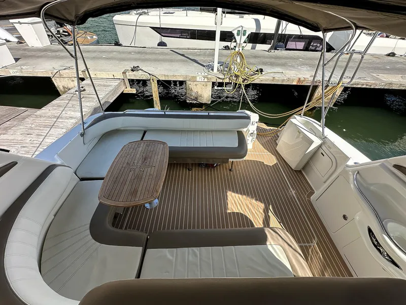 Slide: The Image of 1999 Sea Ray 400 Sundancer yacht interior with seating and wooden table at dock. - 12