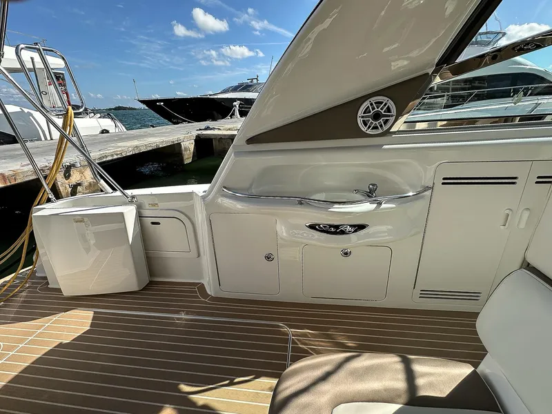 Slide: The Image of 1999 Sea Ray 400 Sundancer yacht interior with sink and seating, docked by the water. - 13