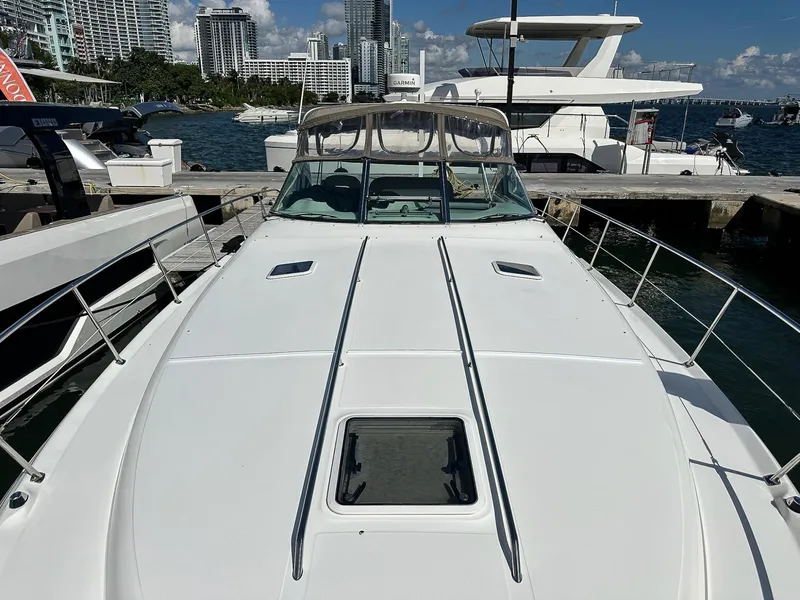Slide: The Image of 1999 Sea Ray 400 Sundancer yacht docked in a marina with city skyline background. - 24