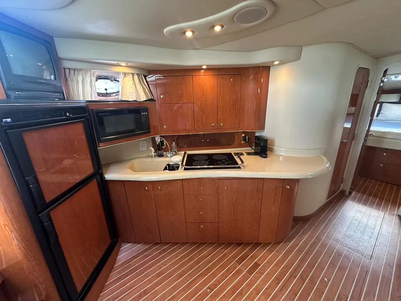 Slide: The Image of 1999 Sea Ray 400 Sundancer yacht kitchen with wood cabinetry, stove, and appliances. - 38