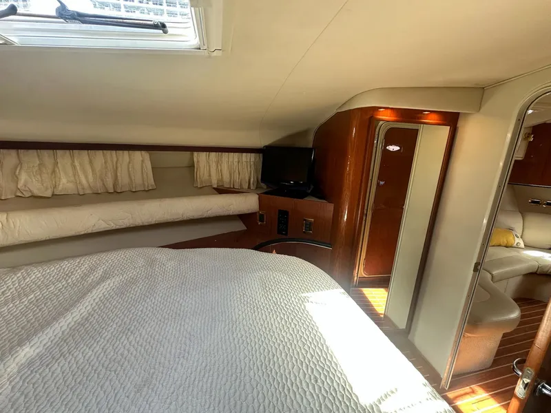 Slide: The Image of 1999 Sea Ray 400 Sundancer cabin interior with bed, TV, and wooden accents. - 43