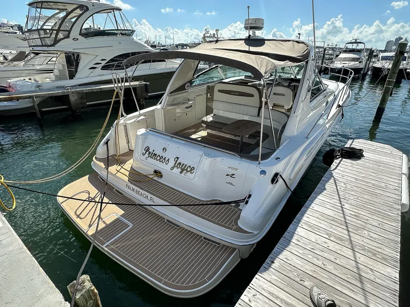 Slide: The Image of 1999 Sea Ray 400 Sundancer docked at marina, featuring spacious deck and canopy. - 5