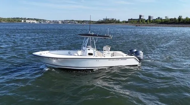 Slide: The Image of 2005 Pursuit 2570 Center Console boat on open water, with cityscape in background. - 0
