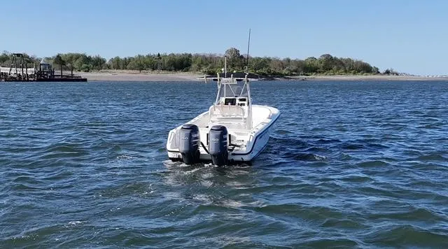 Slide: The Image of 2005 Pursuit 2570 Center Console boat on open water near a shoreline. - 10