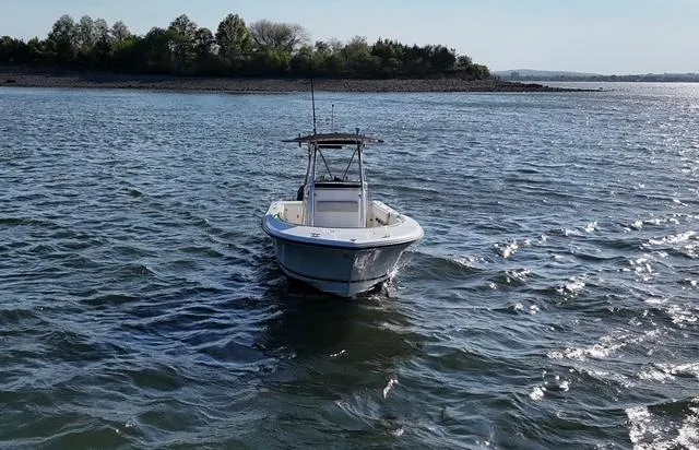 Slide: The Image of 2005 Pursuit 2570 Center Console boat on open water, near a wooded shoreline. - 7