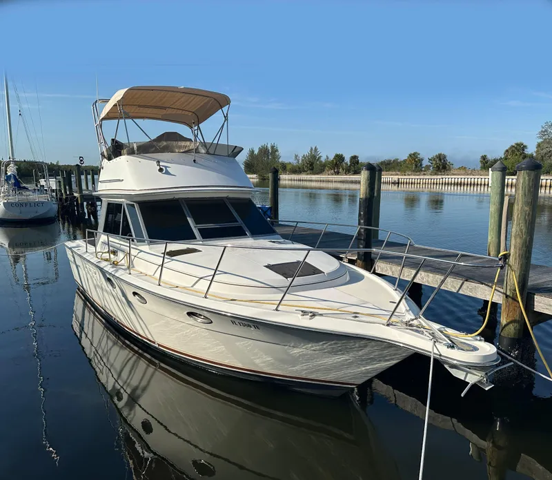 Slide: The Image of 1989 Tiara Yachts 3100 Convertible docked in a serene marina setting. - 0