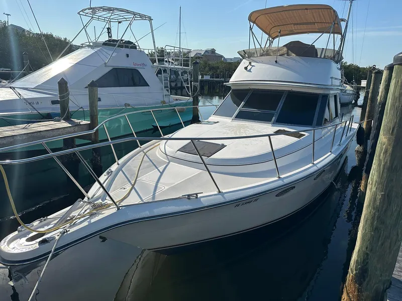 Slide: The Image of 1989 Tiara Yachts 3100 Convertible docked at marina, featuring sleek design and spacious deck. - 1